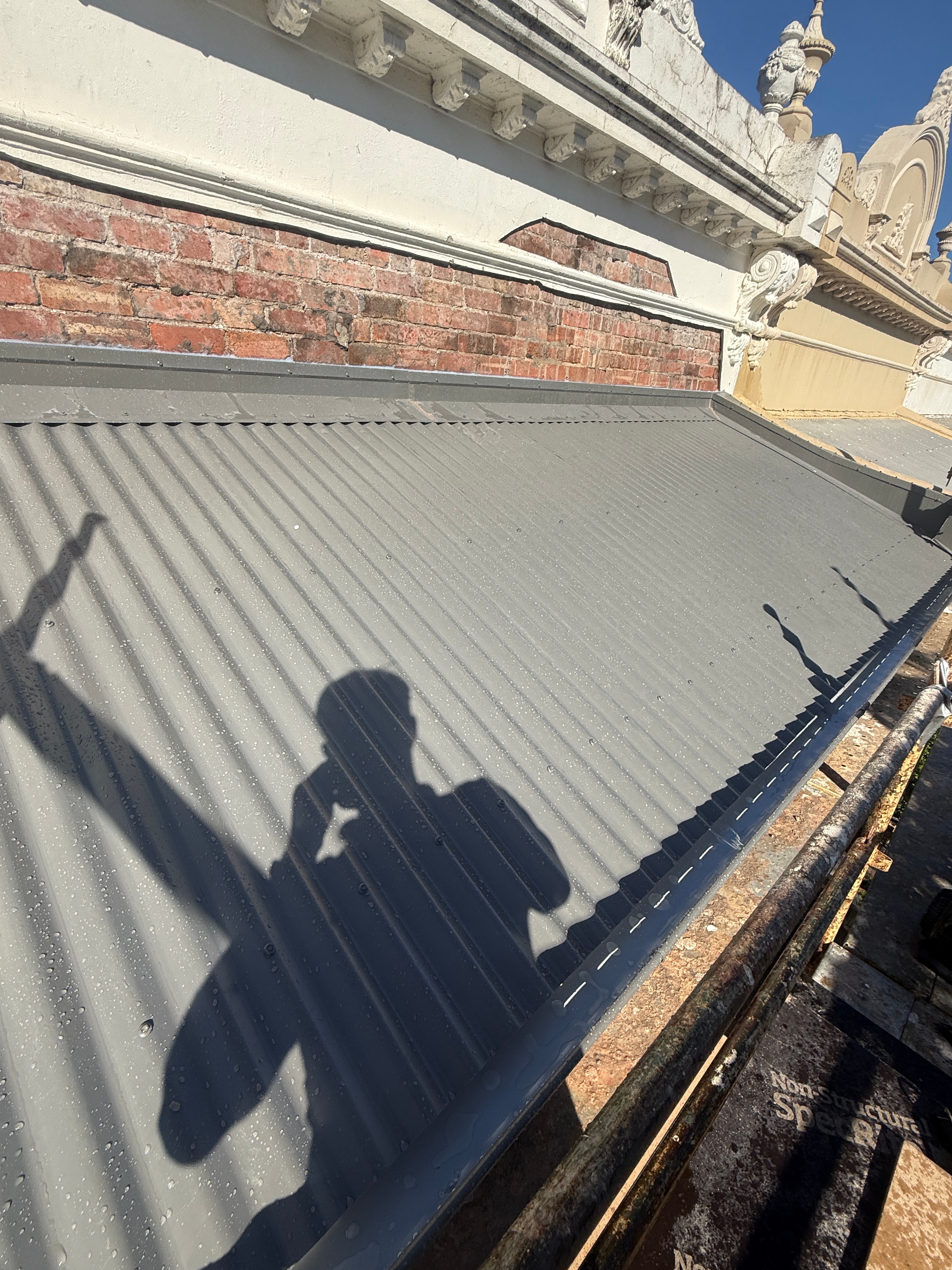 Klip-Lok metal roof at sunset with Melbourne skyline in background